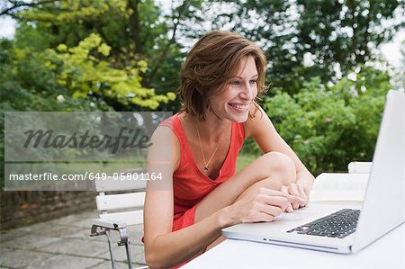 Femme souriante, à l'aide d'ordinateur portable dans la Cour