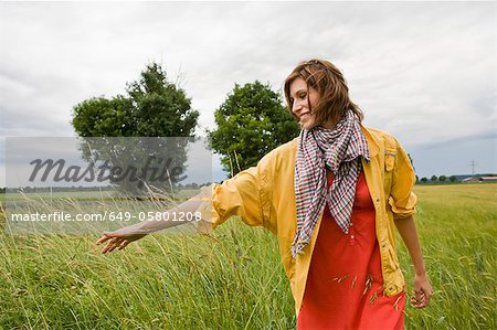 Femme souriante, marchant dans les herbes hautes