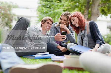 Étudiants à l'aide de téléphone portable sur l'herbe