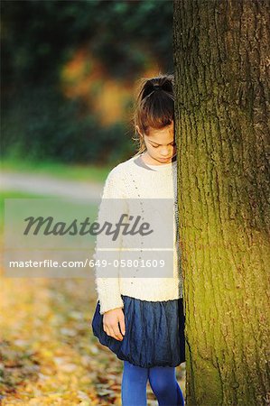 Jeune fille se penchant sur l'arbre dans le parc