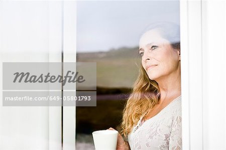 Femme jouissant de la tasse de café à la fenêtre