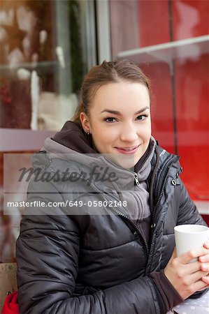 Smiling woman having coffee outdoors