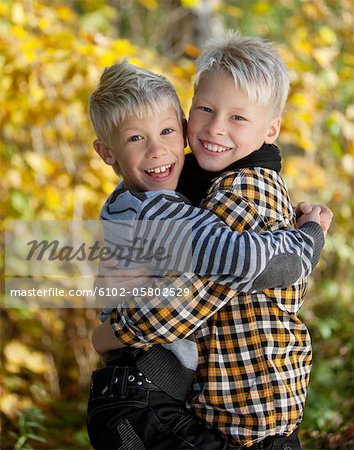Portrait of two blonde boys hugging outside