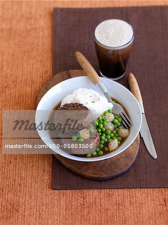 Galette de bœuf, pois, pommes de terre pilées et verre de bière