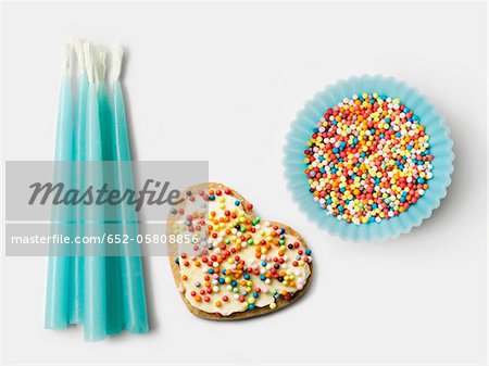 Bougies d'anniversaire bleu, biscuits décorés et une tasse de papier bleu remplie de billes de sucre