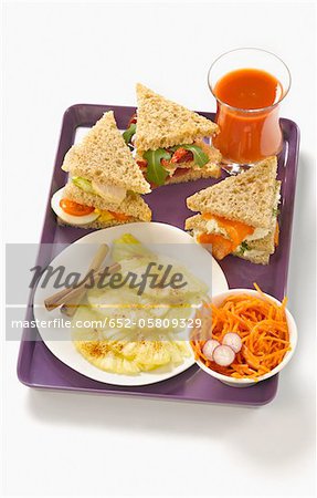 T.V dinner tray with grated carrot salad,sandwiches and pineapple with cinnamon