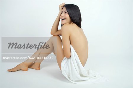 Nude woman partially covered with towel, full length portrait