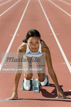 Woman crouched in starting position on running track