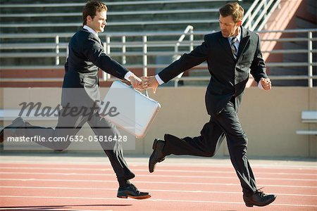 Businessmen handing off briefcase in relay race