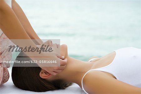 Young woman receiving face massage, side view