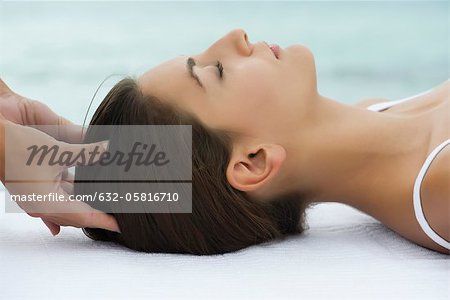 Young woman receiving head massage, side view