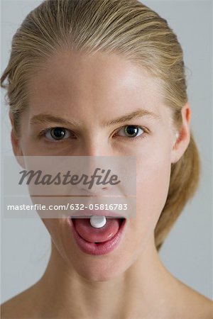 Vitamin pill on young woman's tongue