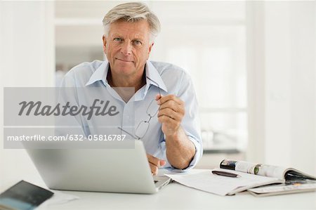 Homme supérieur à l'aide d'ordinateur portable à la maison