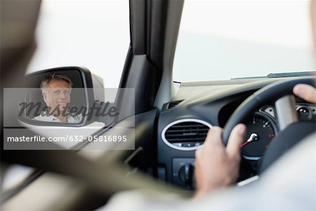 Homme de conduite automobile, reflétée dans le rétroviseur latéral du conducteur