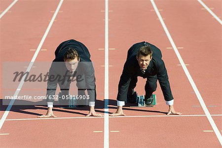 Businessmen crouched in starting position on running track