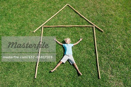 Garçon couché sur l'herbe dans la description de la maison, grande angle vue