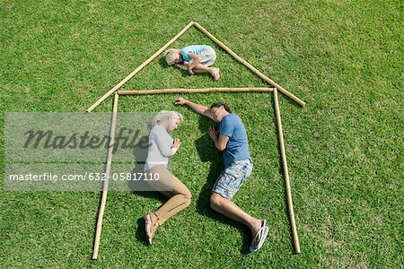 Familie mit einem Kind auf Gras auf Umriss House, hoher Winkel Ansicht liegend