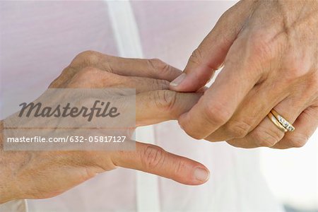 Senior woman rubbing knuckles, cropped