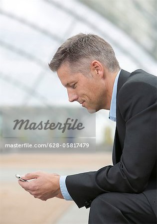 Homme d'affaires avec téléphone cellulaire, vue latérale