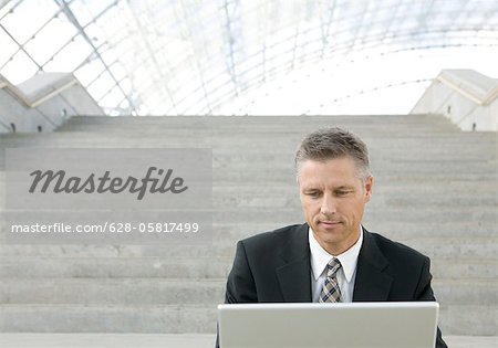 Homme d'affaires assis sur les escaliers, à l'aide d'ordinateur portable