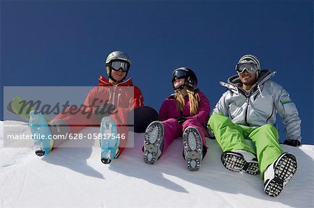 Snowboarder et skieurs assis en demi-lune