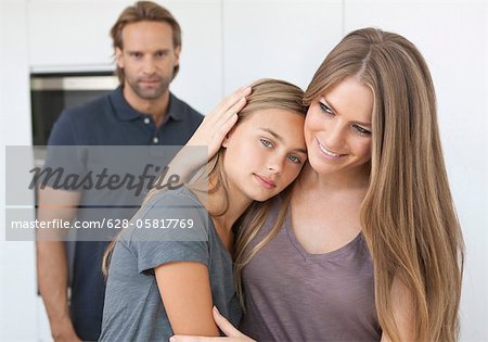 Mère et fille rapprochés avec le père en arrière-plan