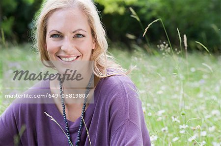 Femme souriante assise dans le champ de blé