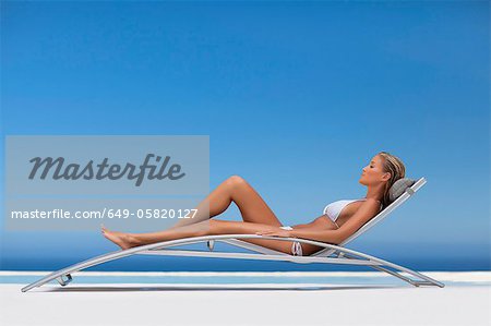 Woman relaxing in modern chair by pool