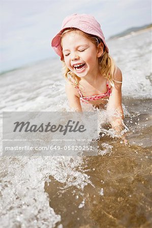 Smiling girl playing in waves on beach