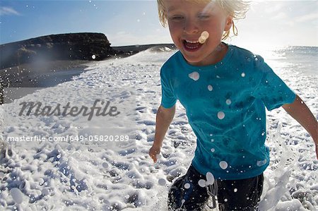 Jungen spielen in Wellen am Strand