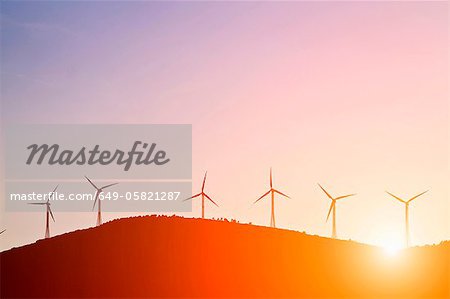 Silhouette of windmills on rural hills