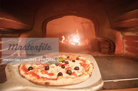 Chef pulling pizza from oven