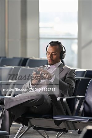 Businessman Wearing Headphones in Waiting Area of Airport