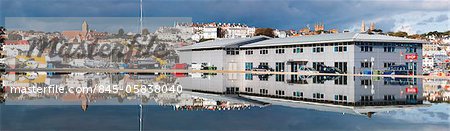 Panorama of St Peter Port and harbour side boats stored on dry dock reflected in a model boat pond in Guernsey, Channel Islands, UK