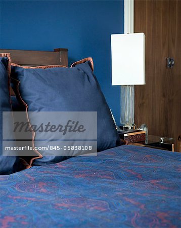 Blue and orange cushions on bed in Addison Road, UK.
