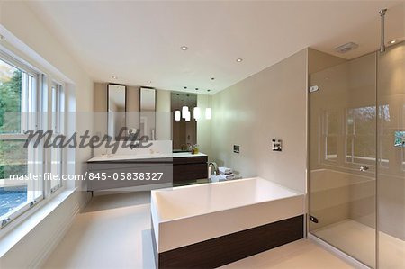 View of modern bath, double-width wash basi and glass shower enclosure in a new build house in Virginia Water, Surrey.