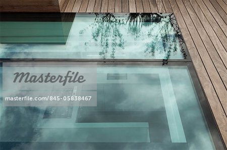 Detail der Dachgarten in Notting Hill, London. Designed by Modular mit MRJ Rundell & Associates Ltd. Bild zeigt großes Glas Blende im gedeckten Dachfläche mit Reflektion von Pflanzen in großen Plantagenbesitzer und Blick auf die Küche. Architekten: Modular