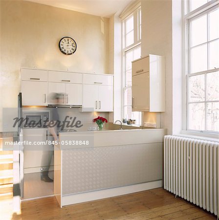 Blurred image of man in modern kitchen decorated in neutral colours. Designed by Designed by Katy Brown