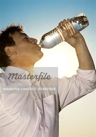 Man outdoors drinking from bottle of water