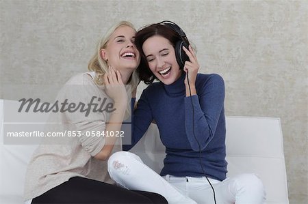 Two girl friends listening music on sofa