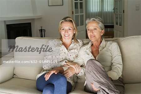 Mother and daughter watching TV in living room