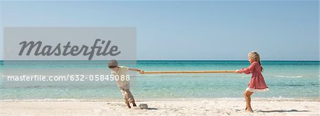 Children playing tug-of-war with bamboo at the beach