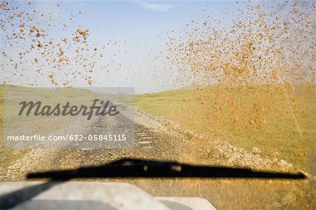 Vu au travers du pare-brise de voiture boueux de route de terre