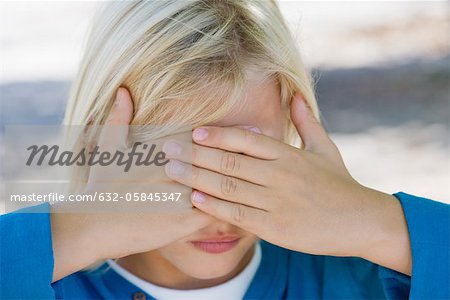 Boy with hands covering eyes