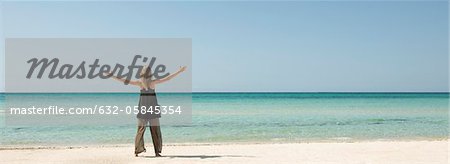 Femme debout sur la plage avec vue arrière bras tendus