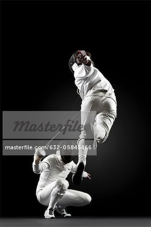 Fencers fencing, one fencer jumping in air