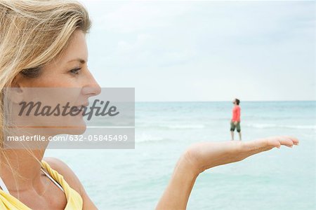 Frau erscheinen kleine Mann in der Hand am Strand zu halten