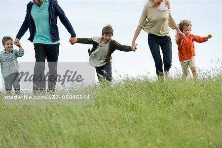 Family running together hand in hand in field