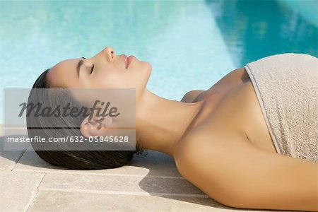 Femme se faire bronzer au bord de piscine