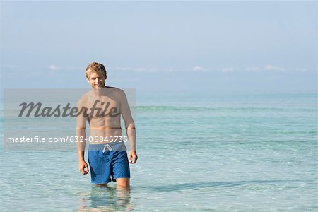 Barechested young man standing knee deep in water, portrait